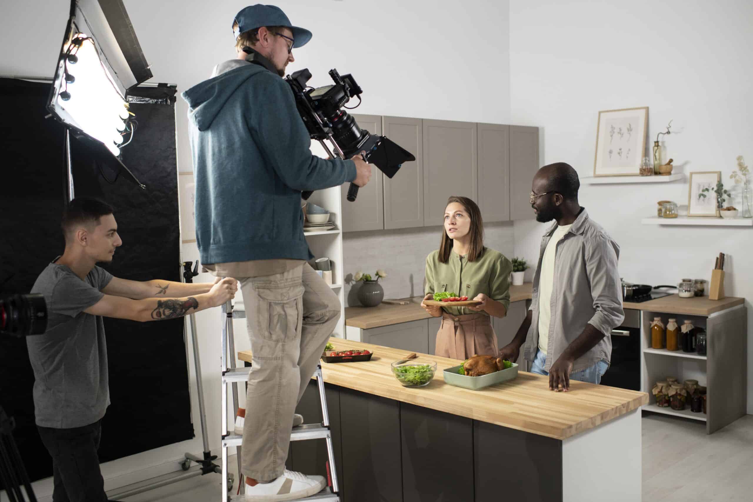 Équipe de tournage filmant un couple en cuisine avec caméra professionnelle et éclairage studio